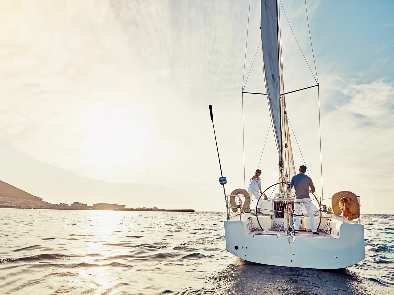 Pareja navegando en velero al atardecer